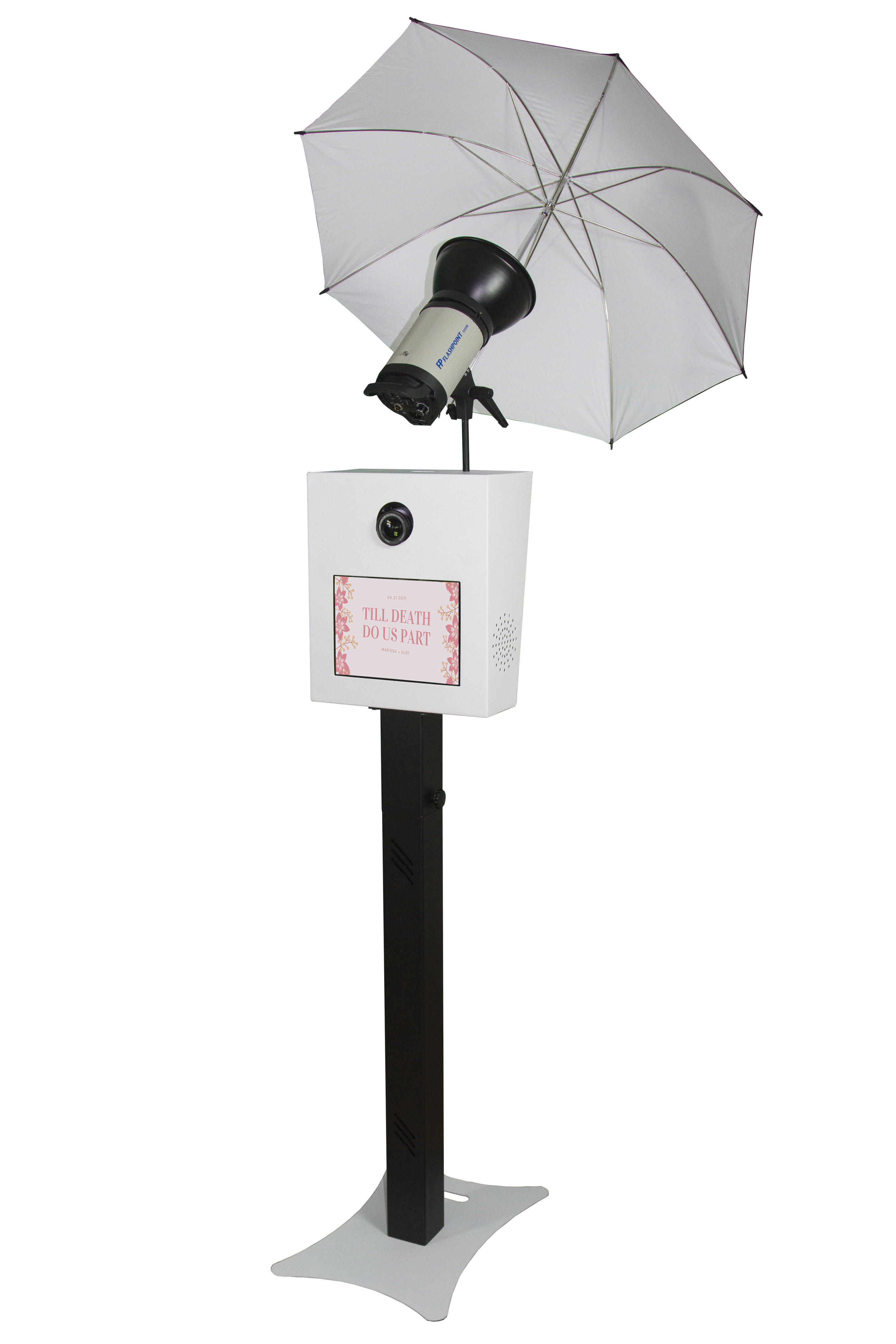 A photo booth with a large umbrella, camera, screen displaying the message "TILL DEATH DO US PART," and a stand.