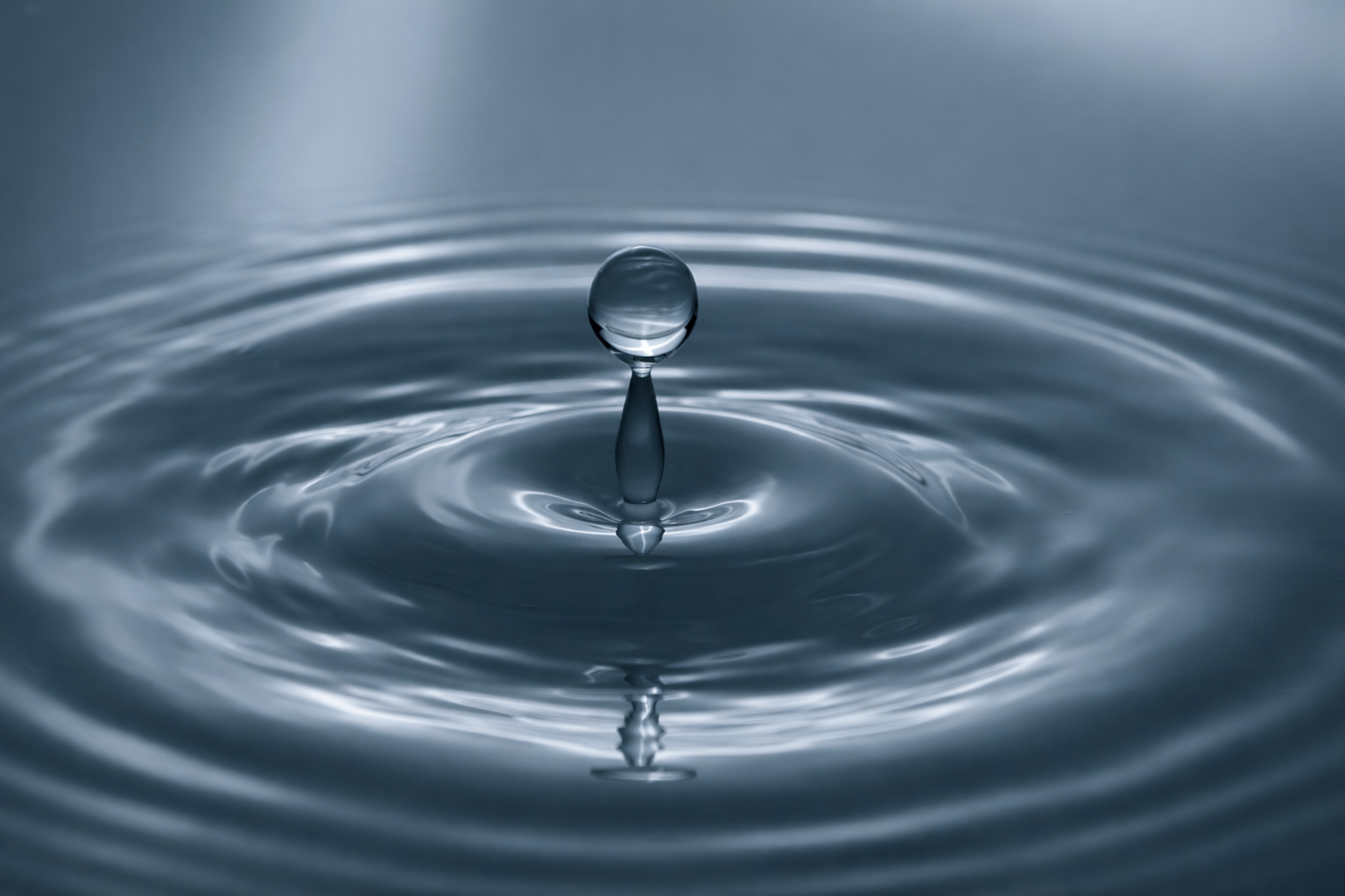 Calm water droplet creating gentle ripples on a blue surface, symbolizing balance and regulation