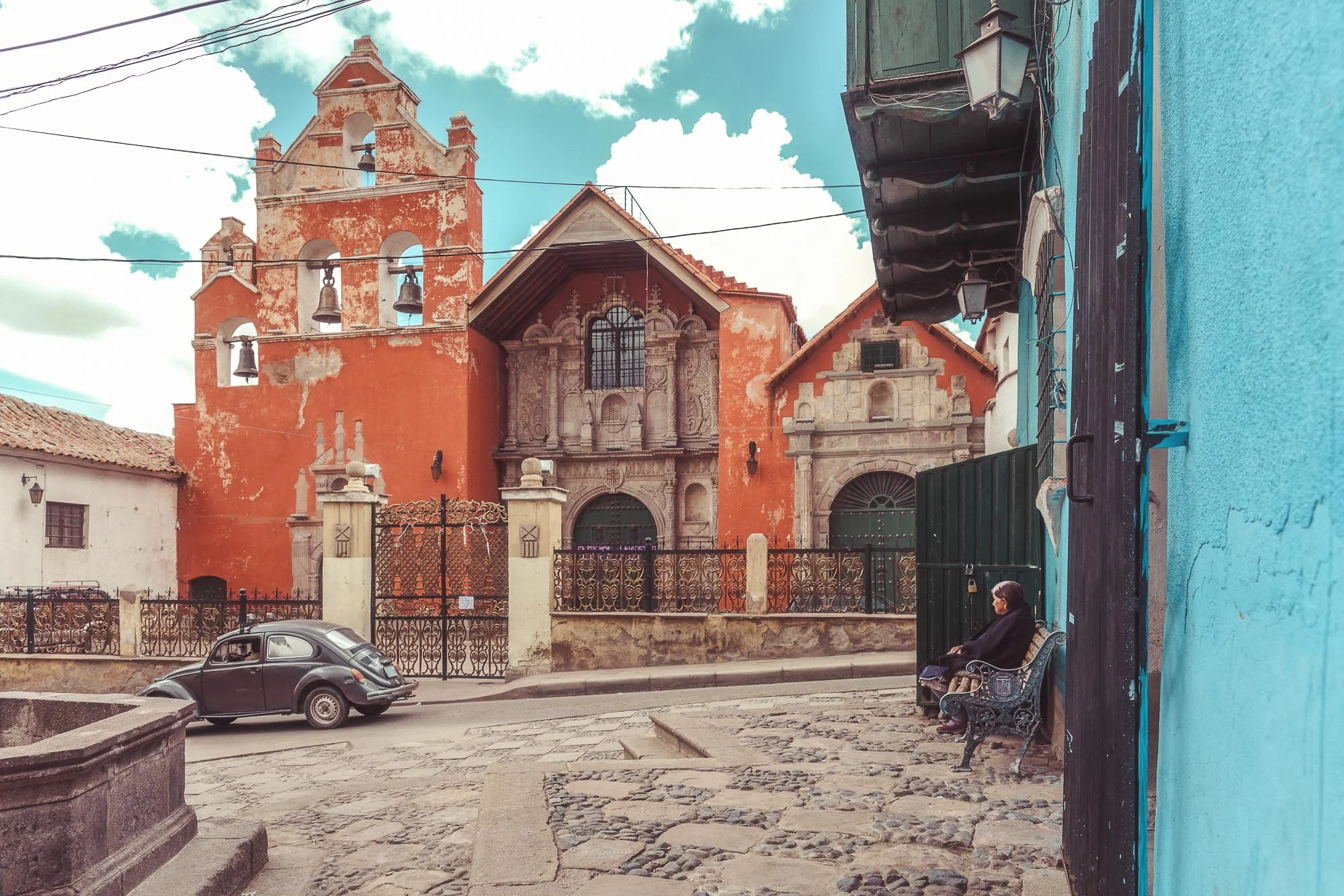 Memories. Bolivian woman looking the passage of a vintage car near the local church. Potosi Bolivia