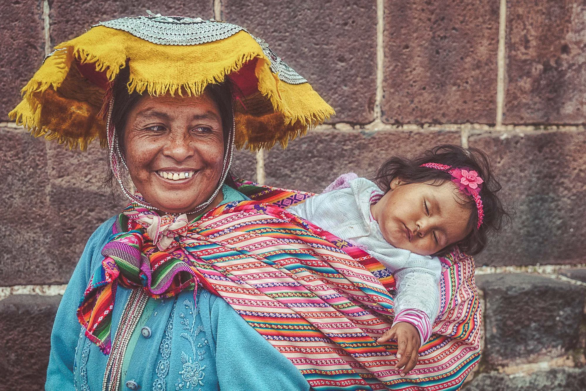 Colourful smile. A mother smiles tenderly watching her daughter sleep. Cuzco, Peru