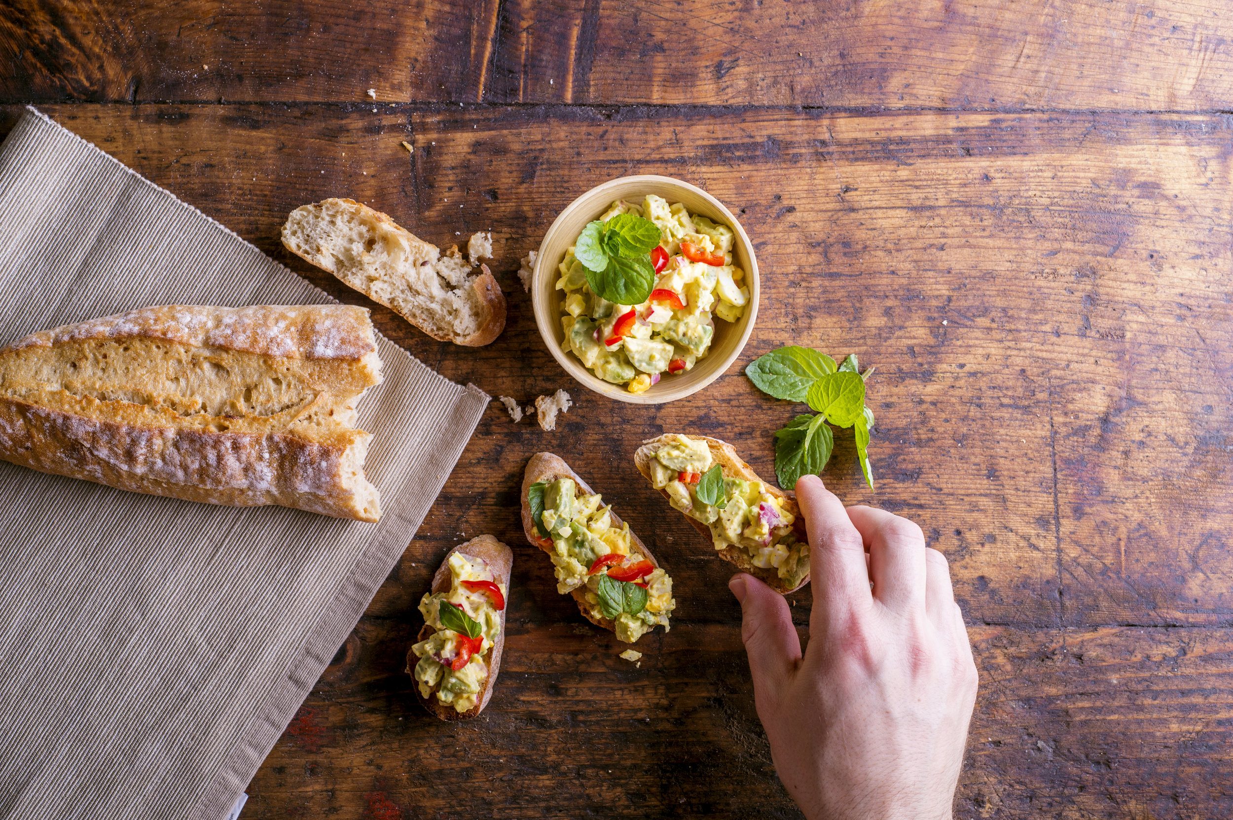 man-taking-avocado-spread-on-bruschetta-slices-PCRLW48.jpg