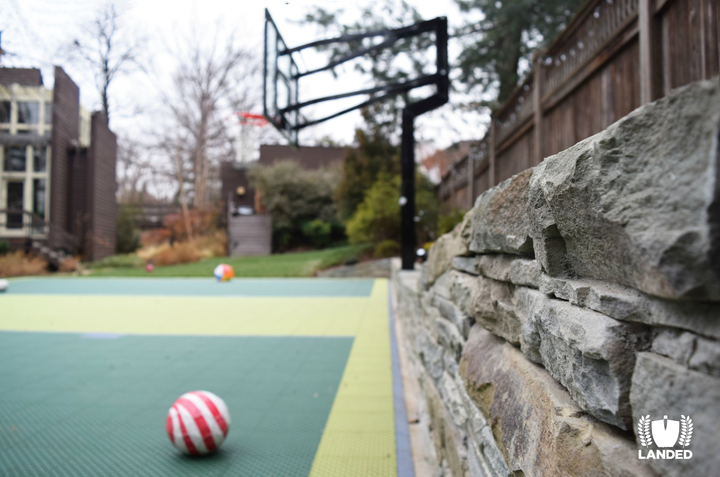 Stacked Stone Wall and a Custom Backyard Sports Court | Landed - Landscape Designers