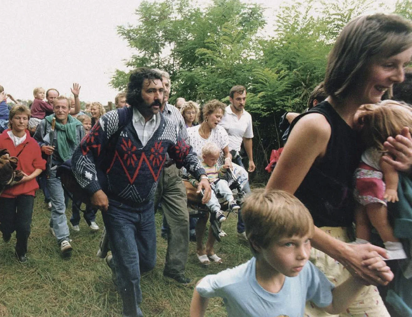 A group East Germans take flight across the Austrian border on August 22 at the border crossing in Klingenbach (Burgenland); an Austrian customs official tells them that they are safe on Austrian territory and will not be sent back.
