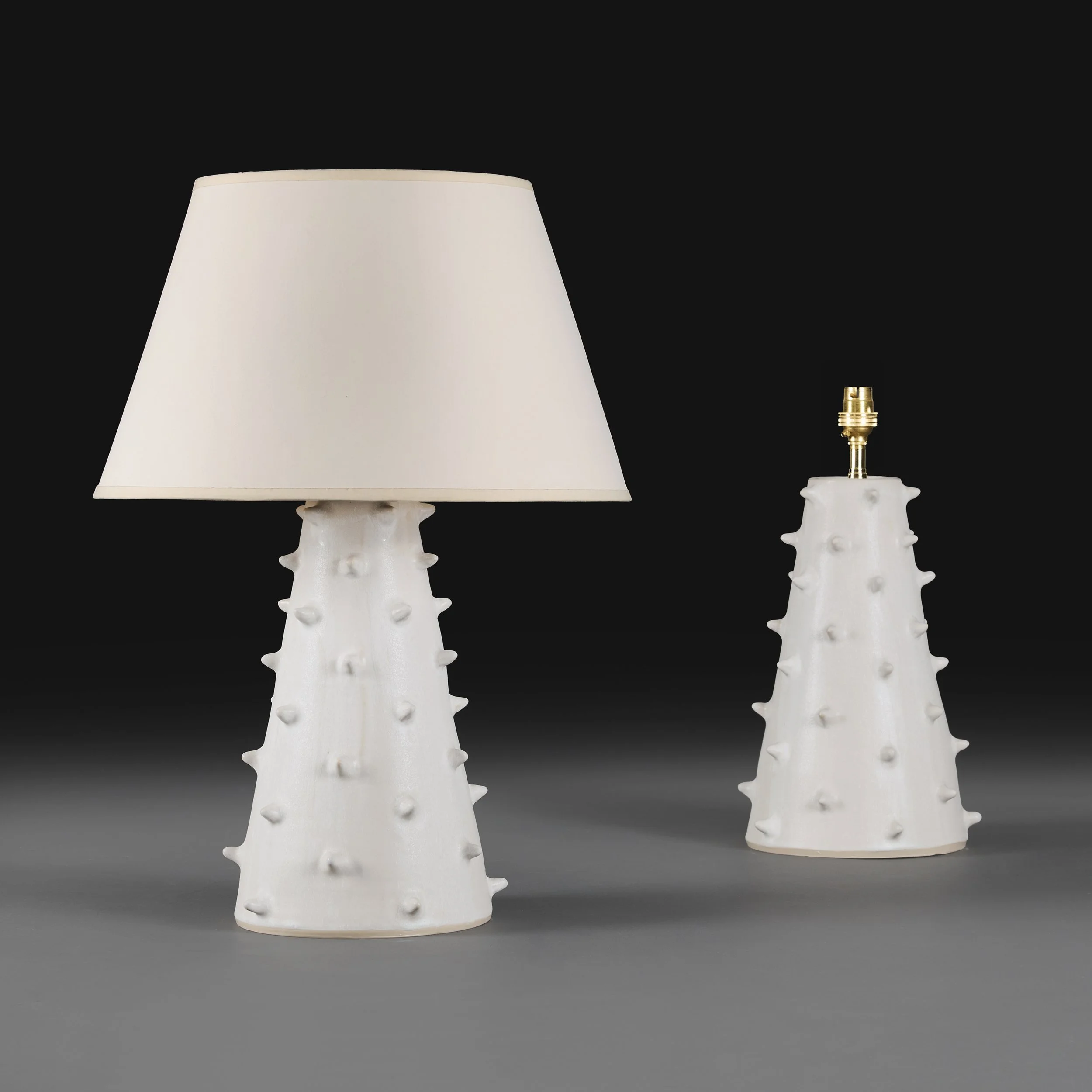 A PAIR OF WHITE SPIKEY ART POTTERY LAMPS