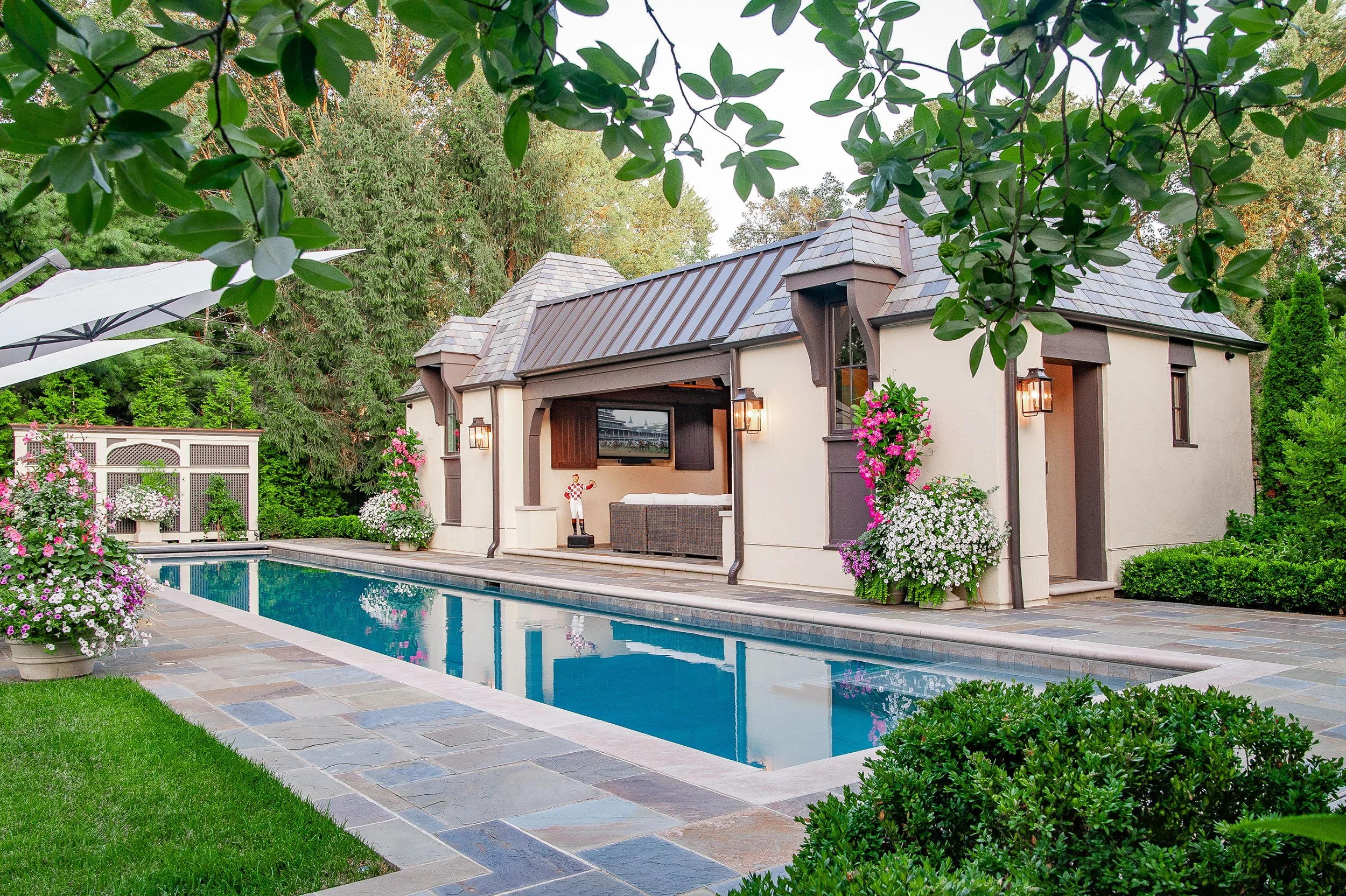 Beautiful backyard pool with an english style pool house and landscape design