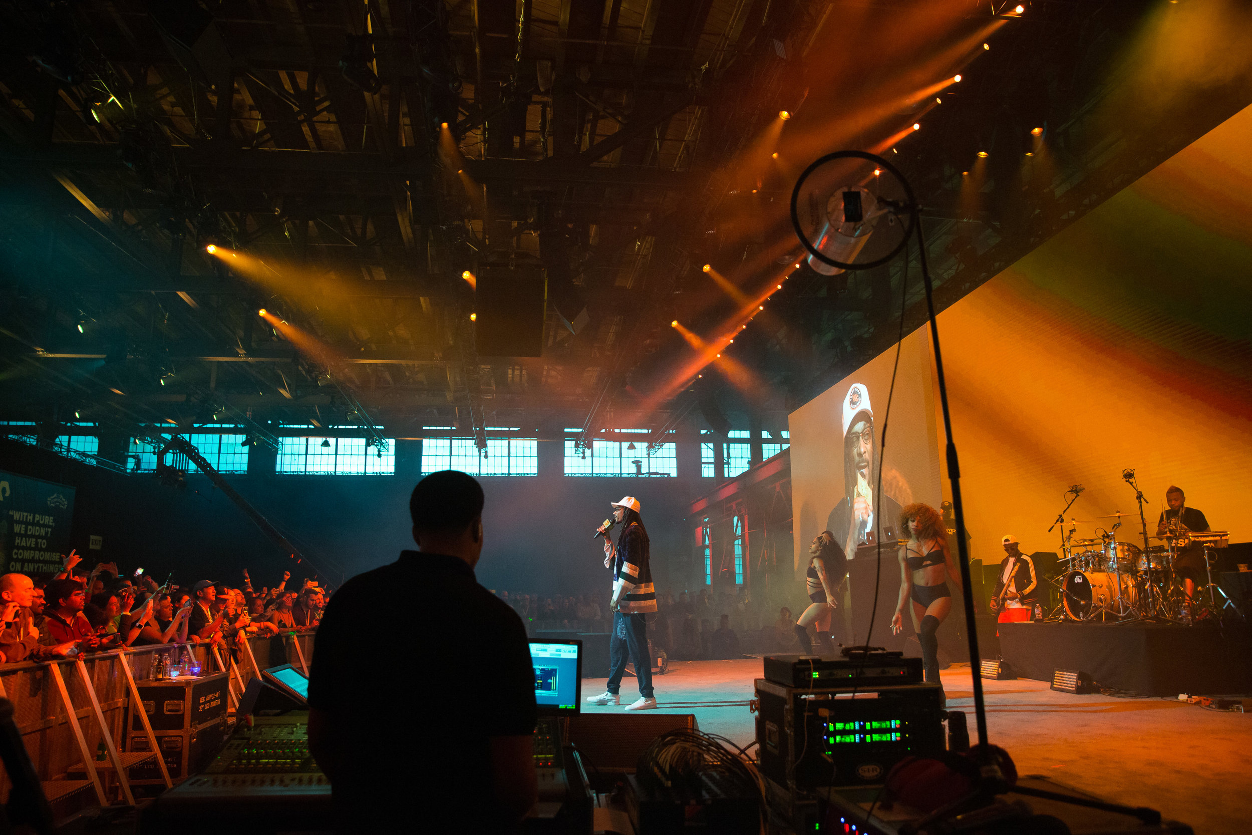  Snoop Dogg performs in orange lighting on stage in front of a crowd 