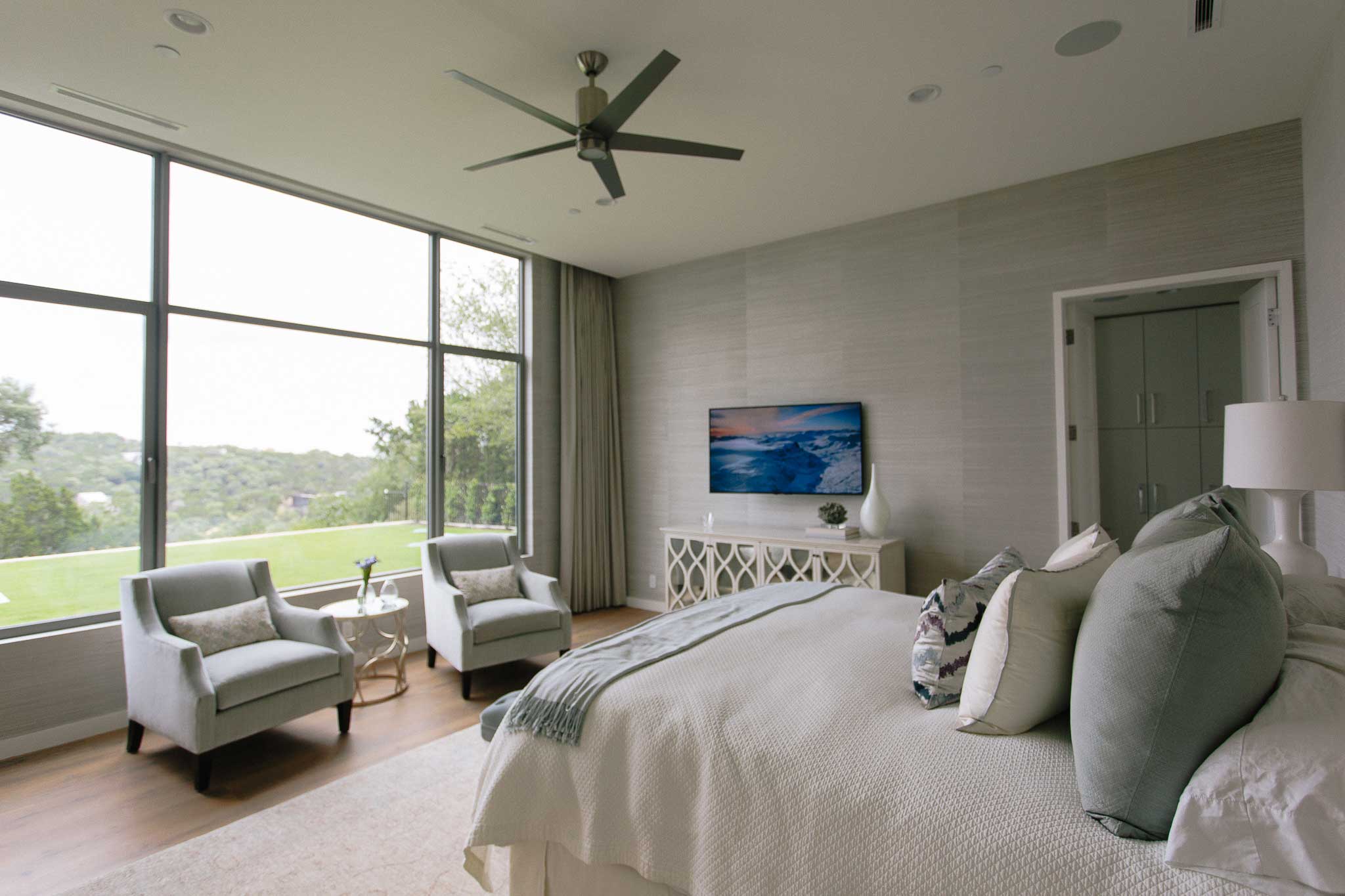 Automated drapes in rich fabric cover the wall-to-wall windows when privacy is desired