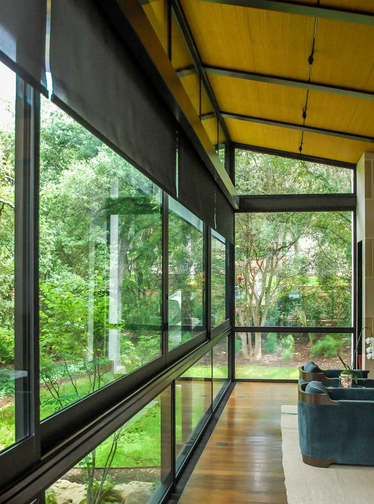 The floor-to-ceiling windows in the formal living room are outfitted with roller shades that are strategically concealed in custom windowpanes