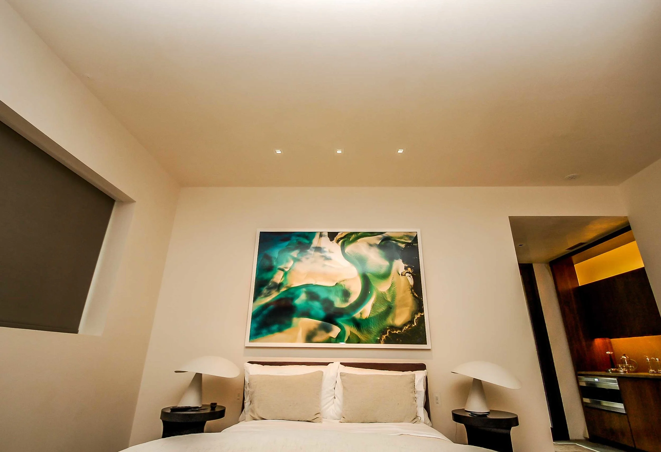 Invisible in-ceiling speakers, a TruFig-ed bedside wall control, and blackout shades within a custom window pocket are all features of the guests quarters
