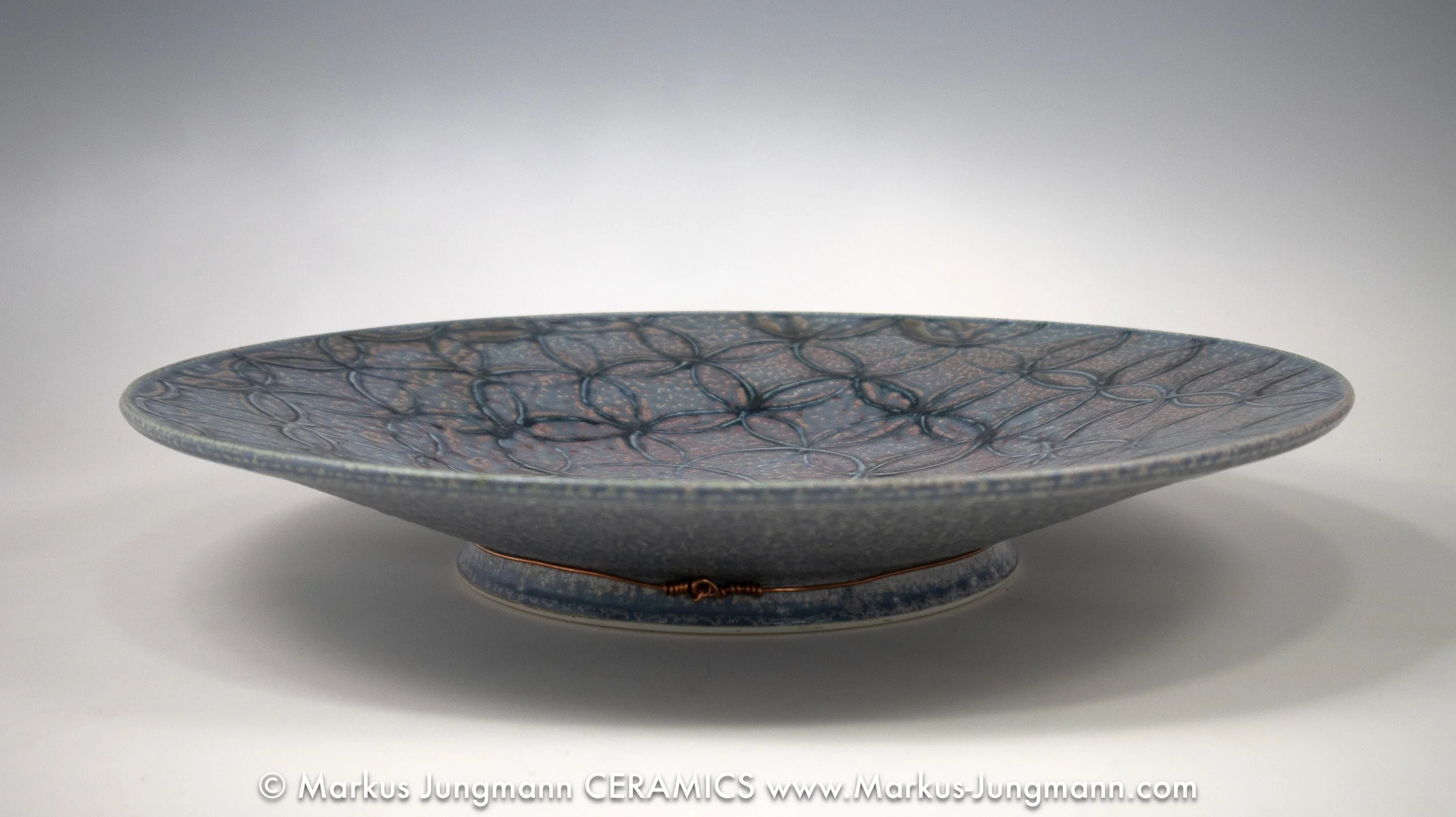 Porcelain bowl with an allover lattice of intersecting circles in slate blue, aubergine and iron-red, by Markus Jungmann side view.