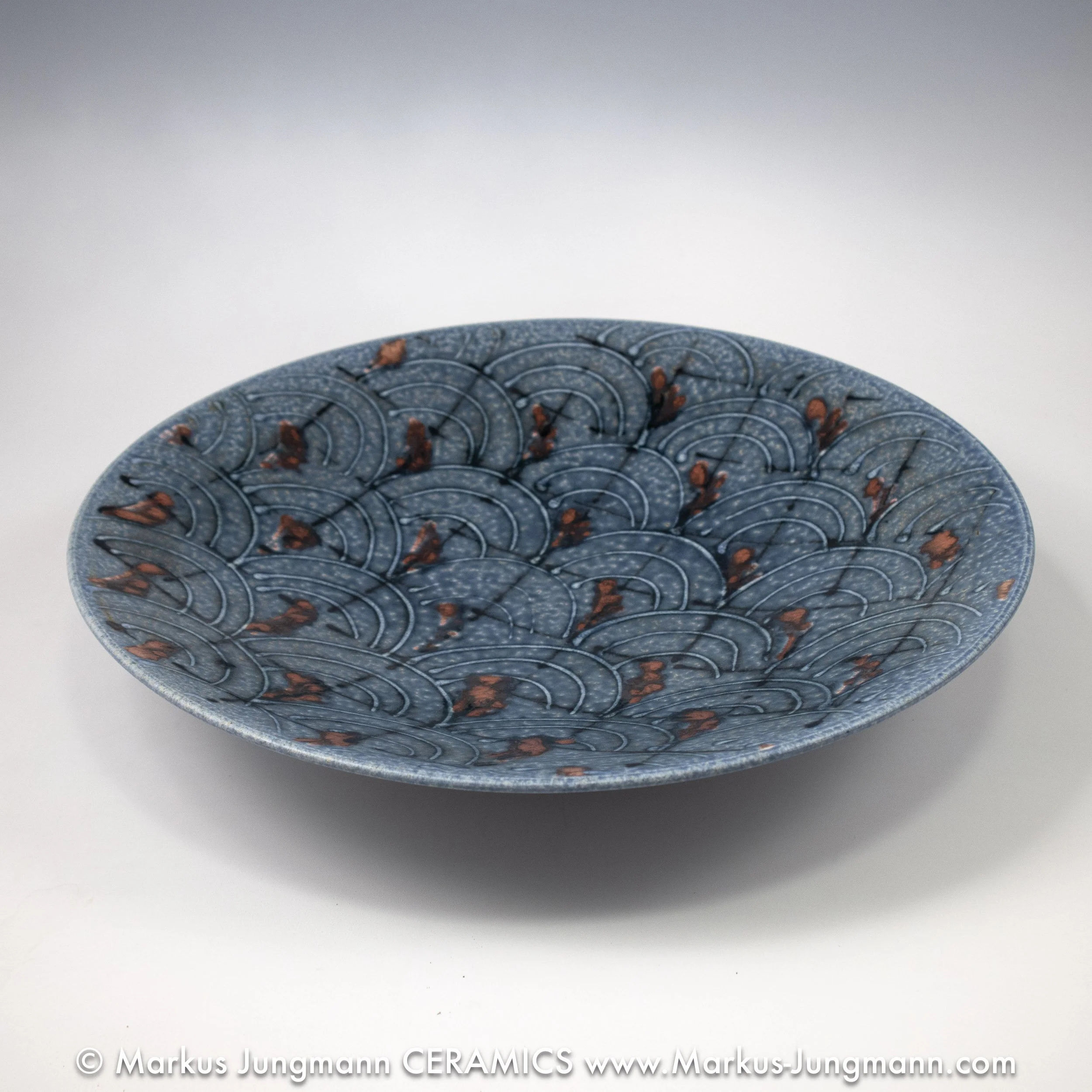 Porcelain bowl with a blue seigaiha wave pattern and iron-red accents on a speckled grey-blue ground, by Markus Jungmann. side view
