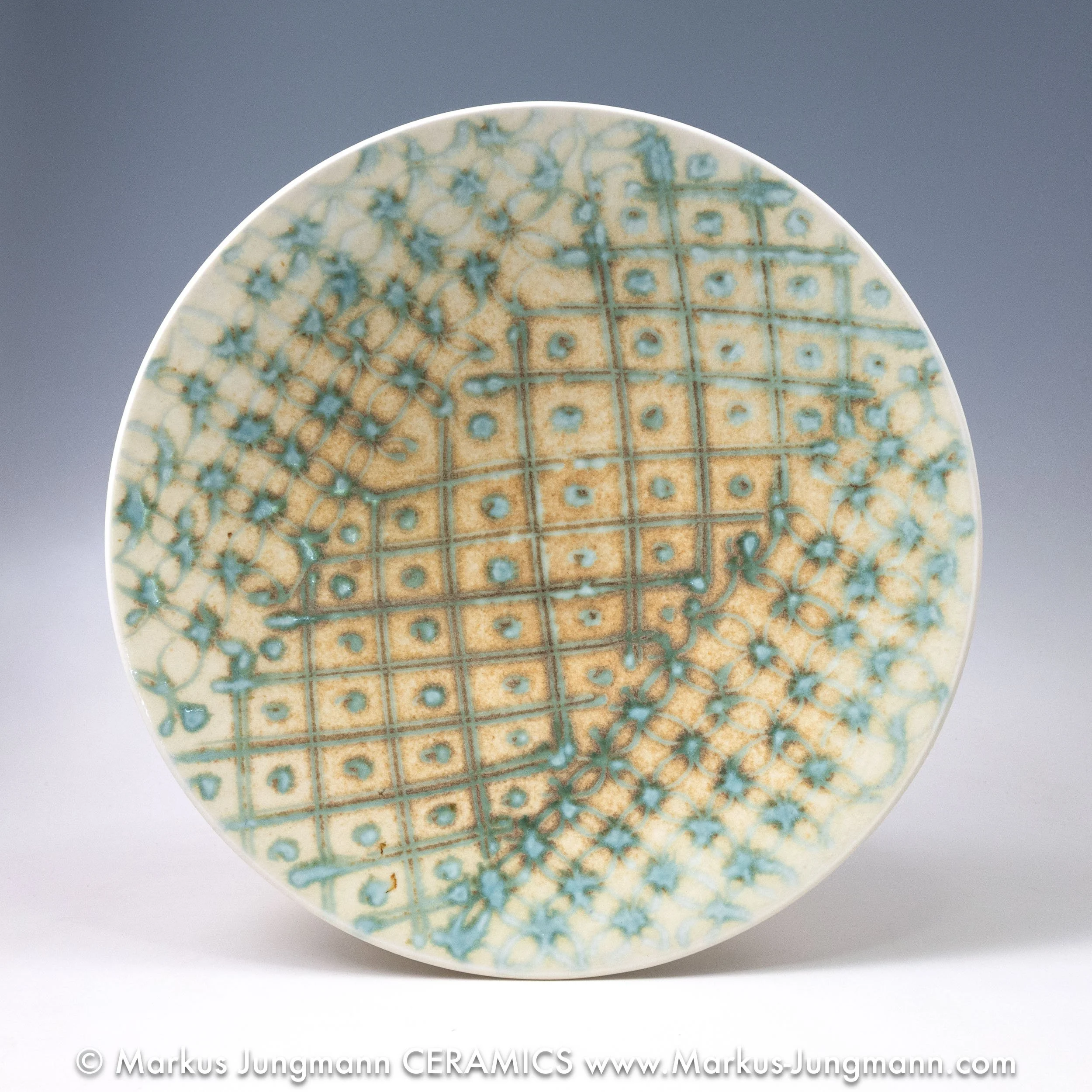 Wheel-thrown porcelain bowl with a teal grid and floral lattice on an oatmeal ground, by Markus Jungmann