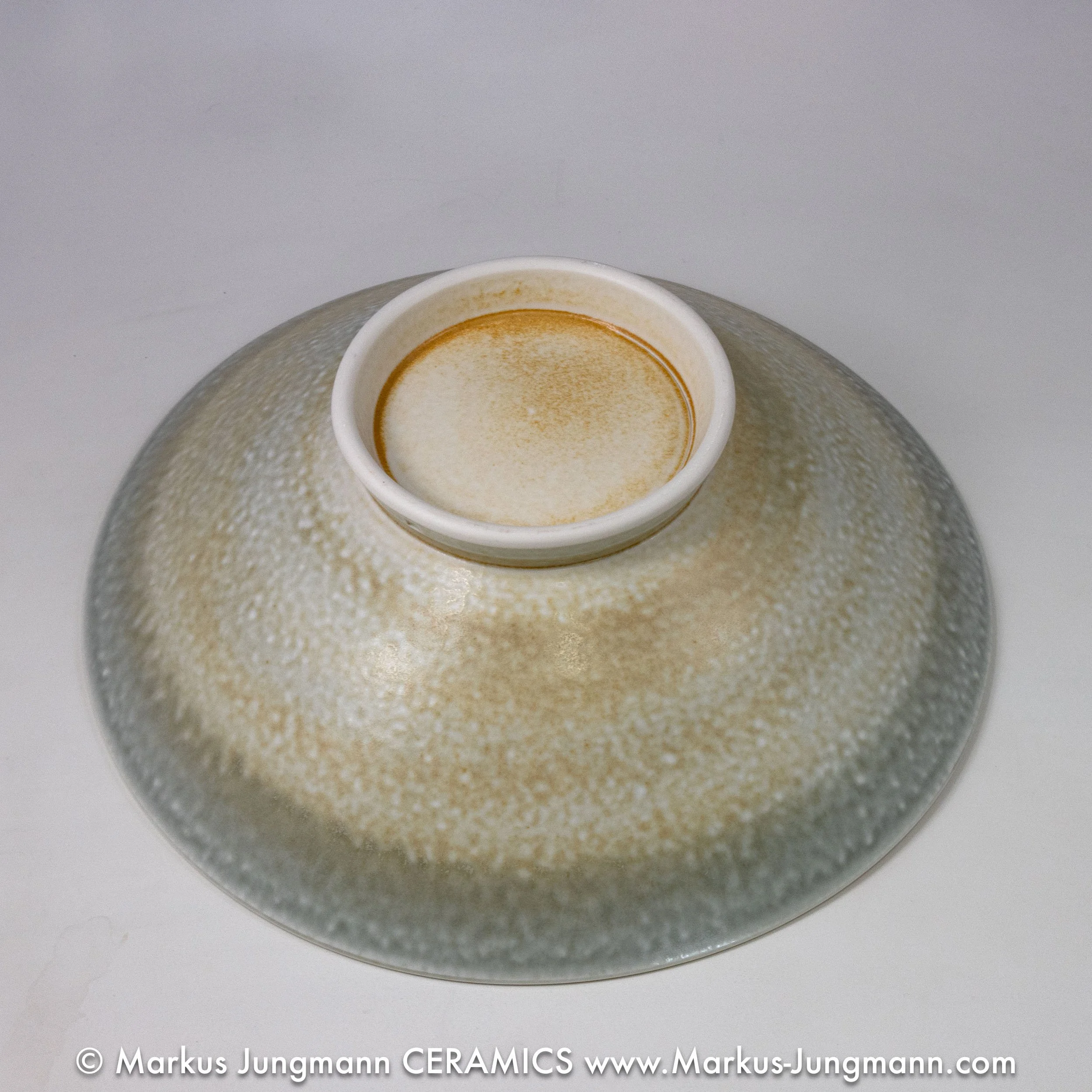 Porcelain bowl with an allover lace-like lattice and turquoise stars on a celadon ground, by Markus Jungmann. bottom view.