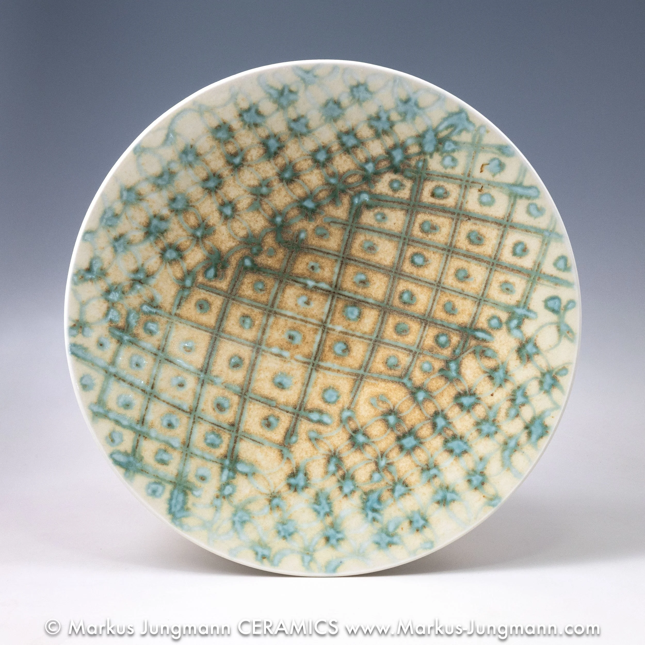 top view, Wheel-thrown porcelain bowl with a teal grid and floral lattice on an oatmeal ground, by Markus Jungmann.