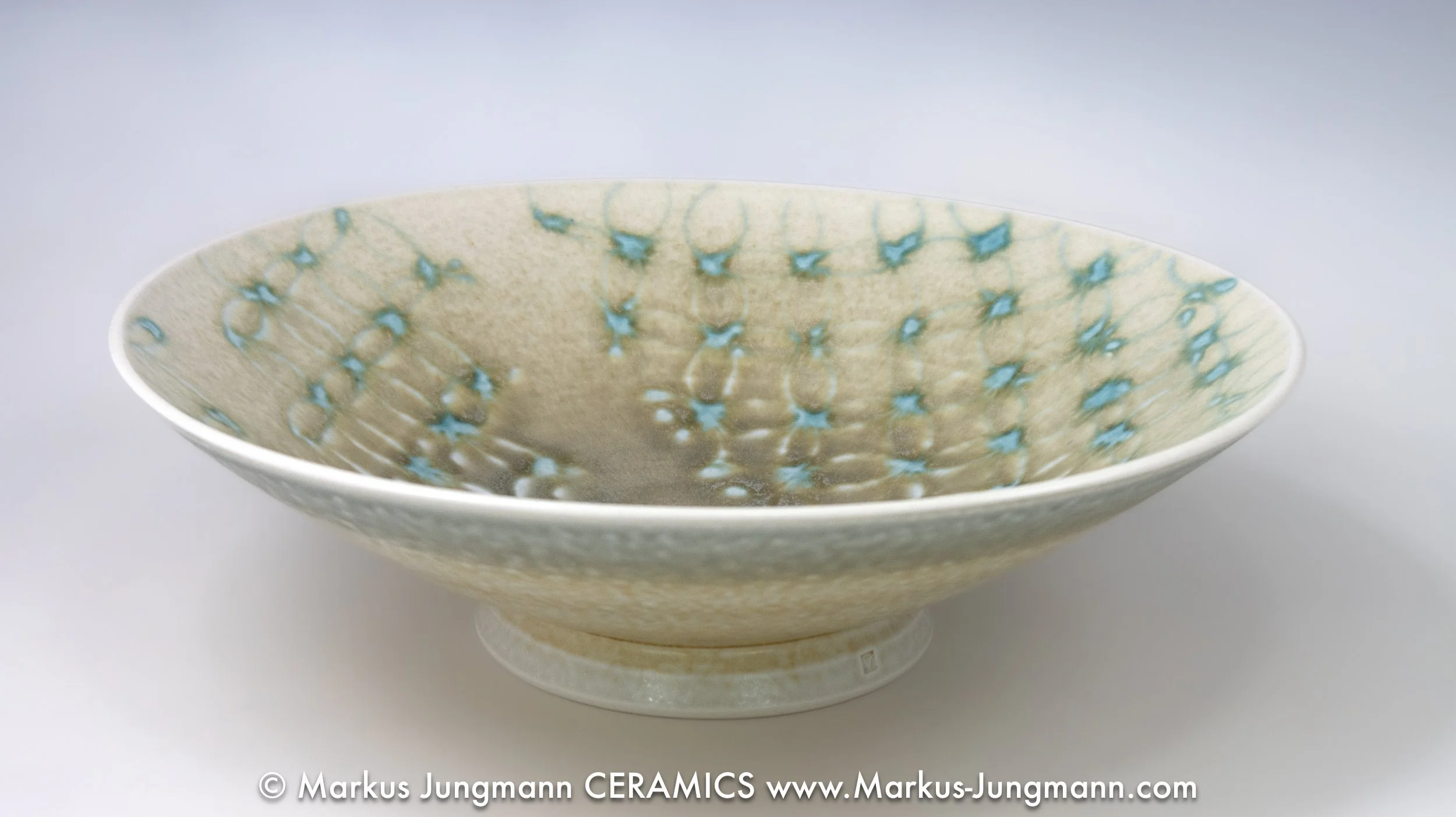 Porcelain bowl with an allover lace-like lattice and turquoise stars on a celadon ground, by Markus Jungmann. side view.