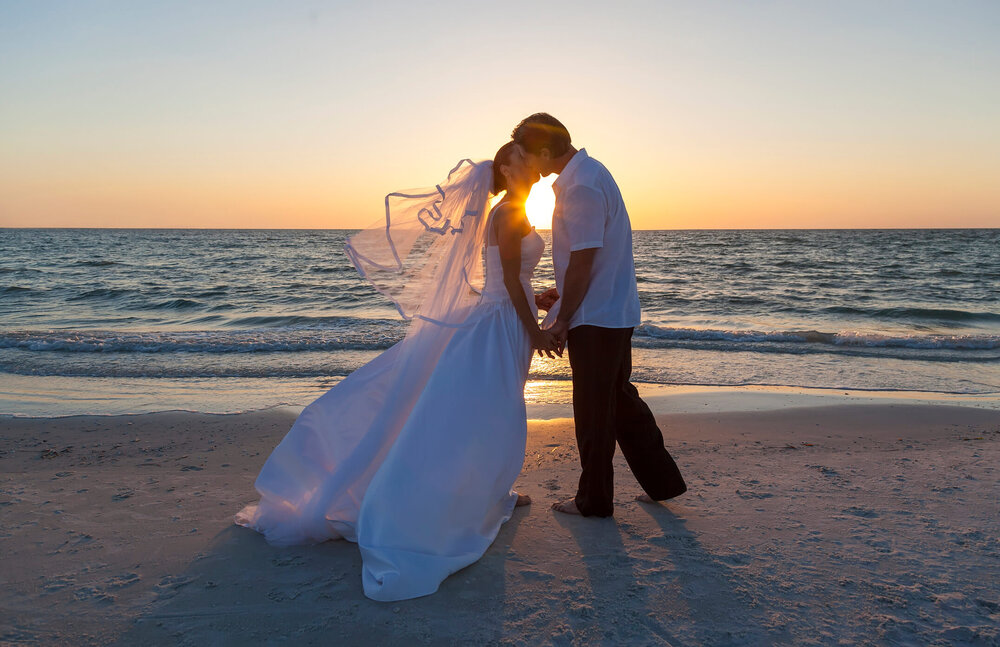 https://images.squarespace-cdn.com/content/v1/597282dd6b8f5bd129c3ae8c/1580307992099-SV7G15GG2X99NMVLK0VD/bride+and+groom+kissing+during+beach+wedding.jpg?format=1000w