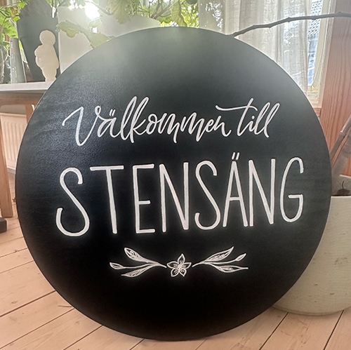 Handmålad gårdsskylt rund svart skylt med vit text