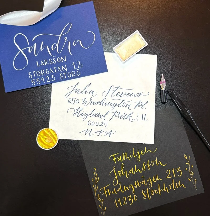 Tre handskrivna bröllopsinbjudningar, kuvert, i blått med vitt bläck, vit med blått skrift och svart kuvert med guldskrift.