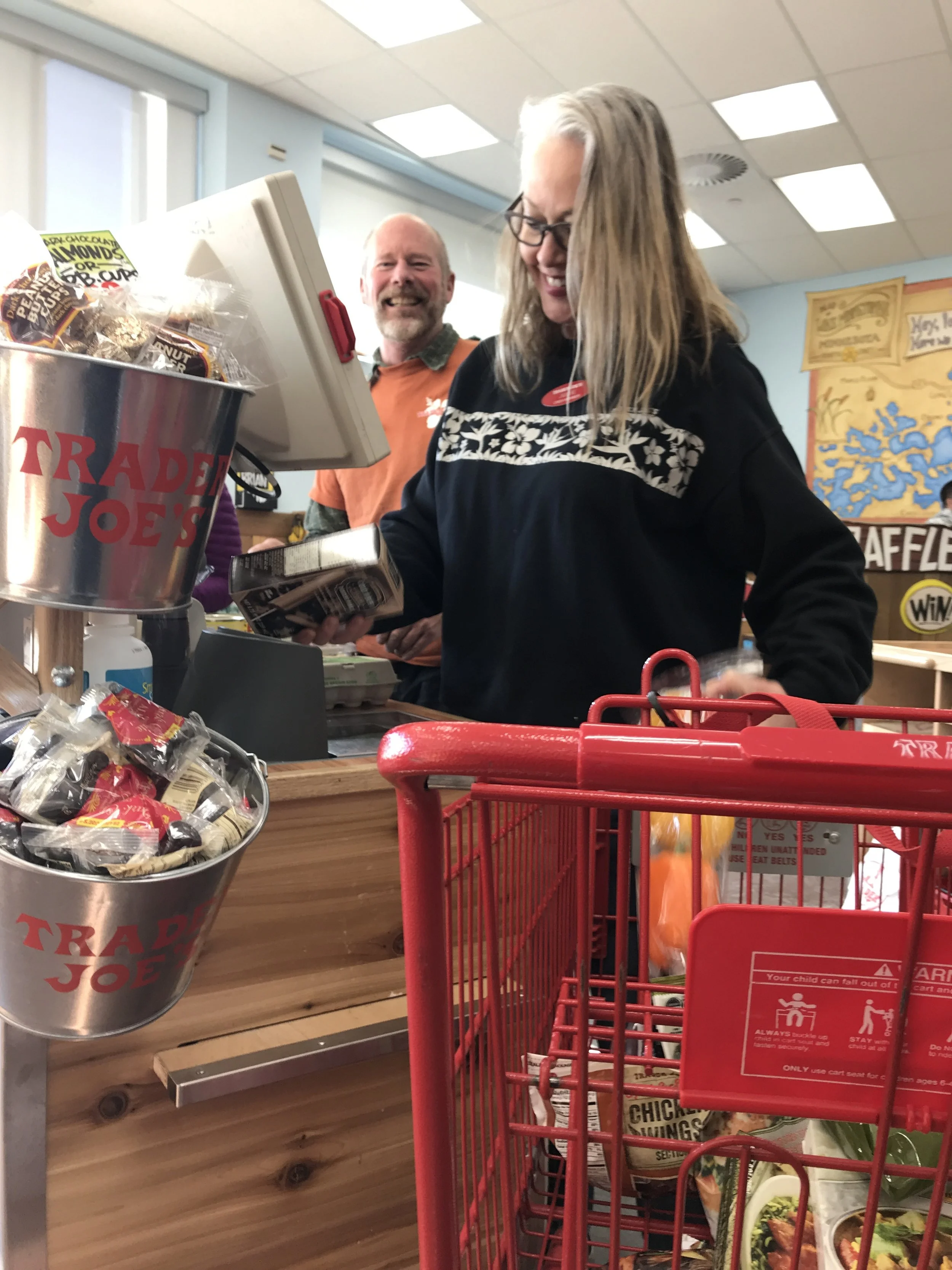A man and woman cashier at Trader Joe's emptying cart.