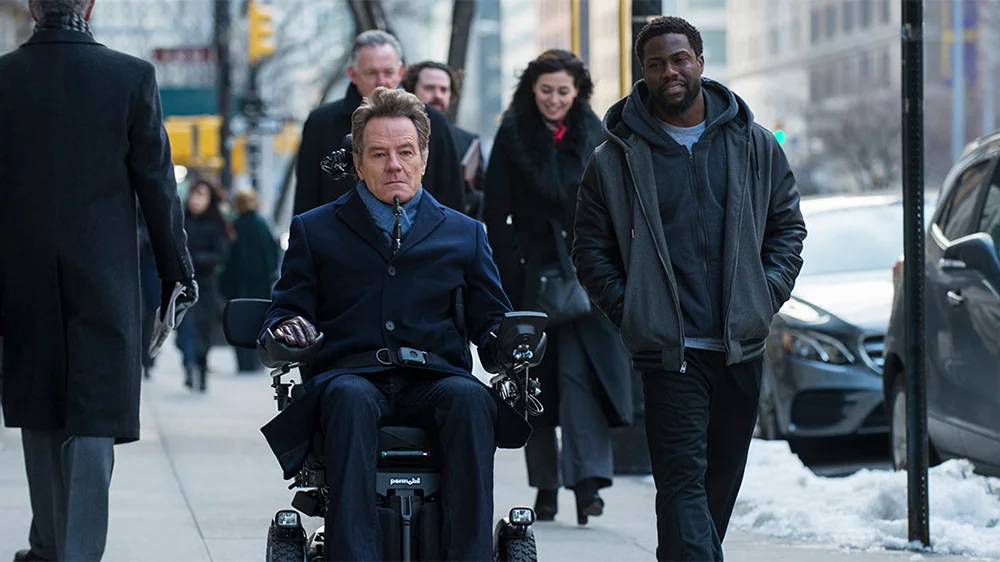 Film still shot with Bryan Cranston in a power wheelchair alongside Kevin Hart for the film “The Upside”