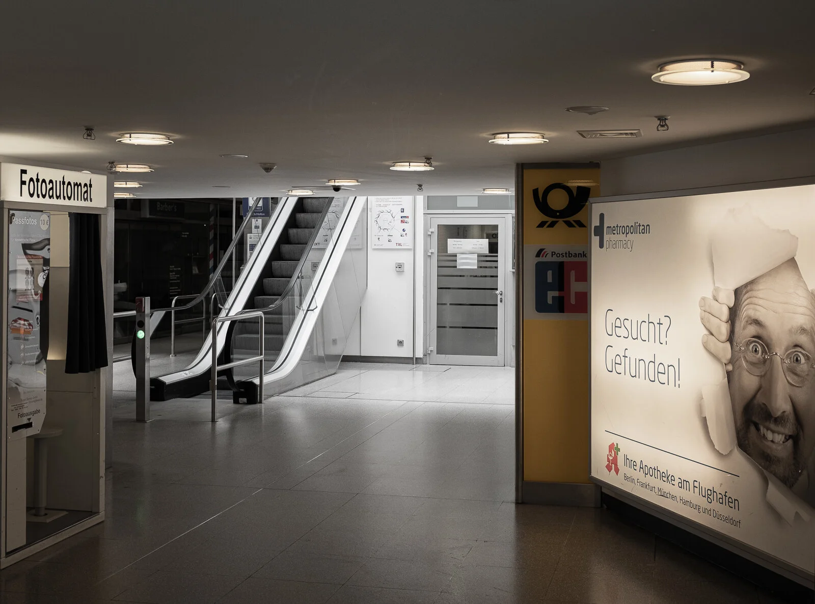 Von der Haupthalle aus gelangt man durch einen düsteren Durchschlupf zu einer Rolltreppe zum Obergeschoss. Dort befinden sich finstere Büros mit dem Staatswappen auf der Tür, und auch eine kleine Galerie, die rechts und links zu zwei Restaurants füh…