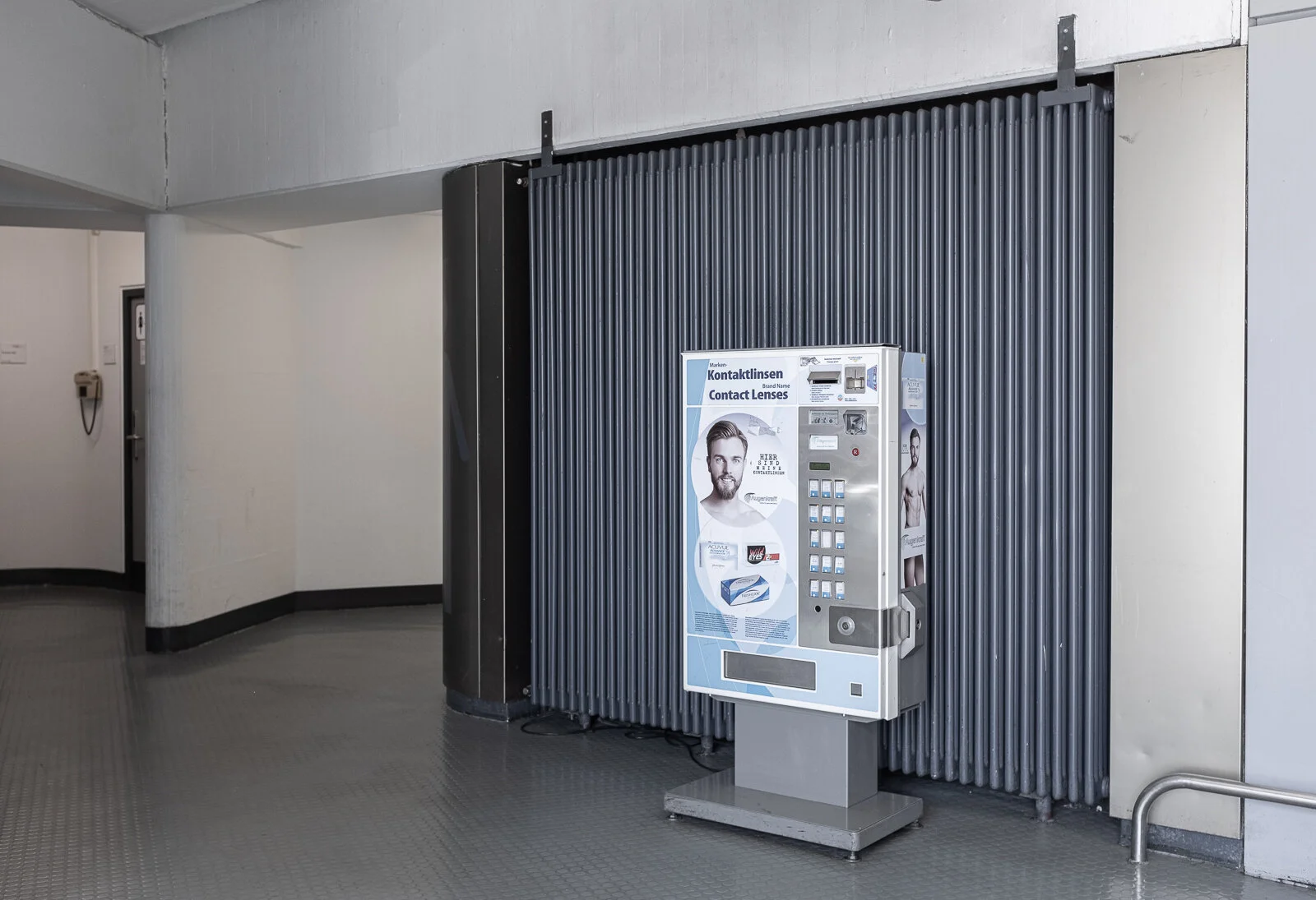 Kontaktlinsenautomat vor Heizkörper. Unten bei den Toiletten.