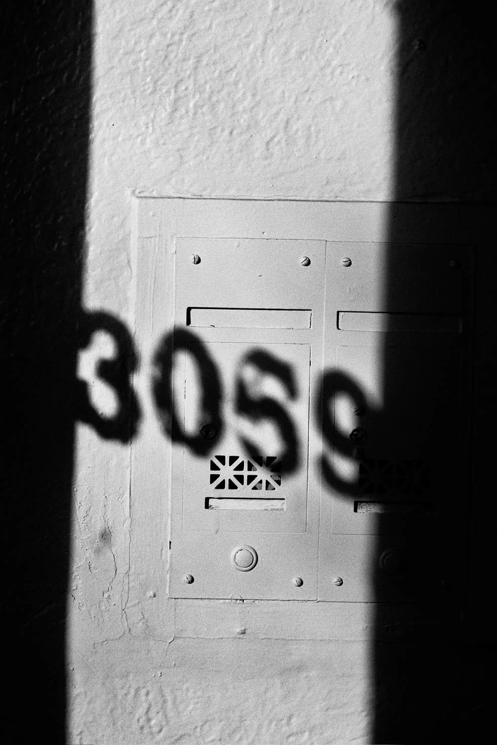 Black and white shadow of an address painted on a window.