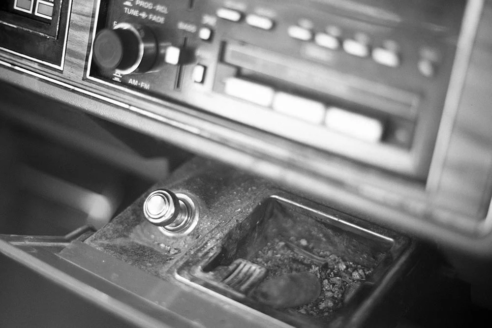 Black and white photo of a cigar butt in the ashtray of a 1989 Buick Park Avenue.