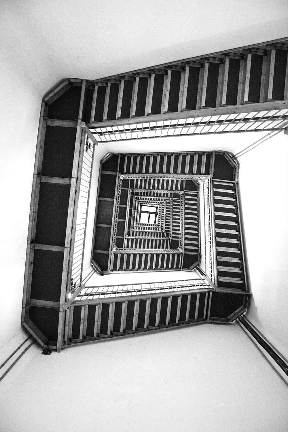 Black and white photo of a spiraling staircase in a walk-up building.