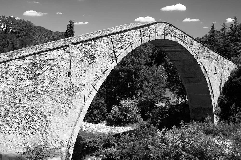 Black and white photograph of the Ponte Alidosi bridge in Castel Del Rio, Italy.