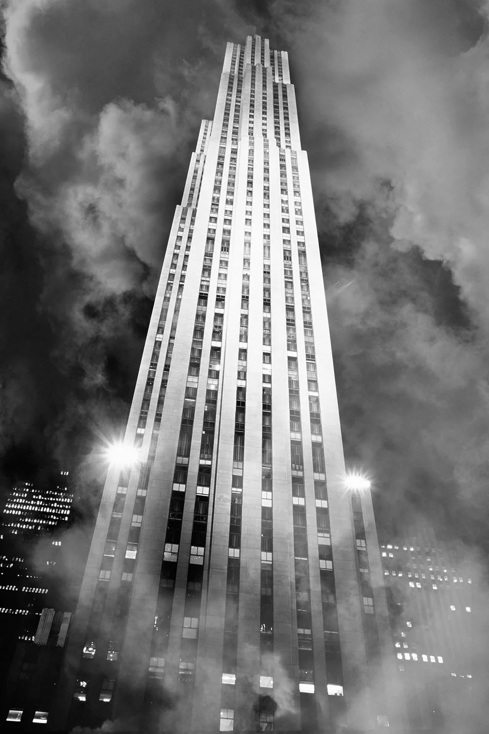 Black and white photograph of Rockefeller Center in fog at night.