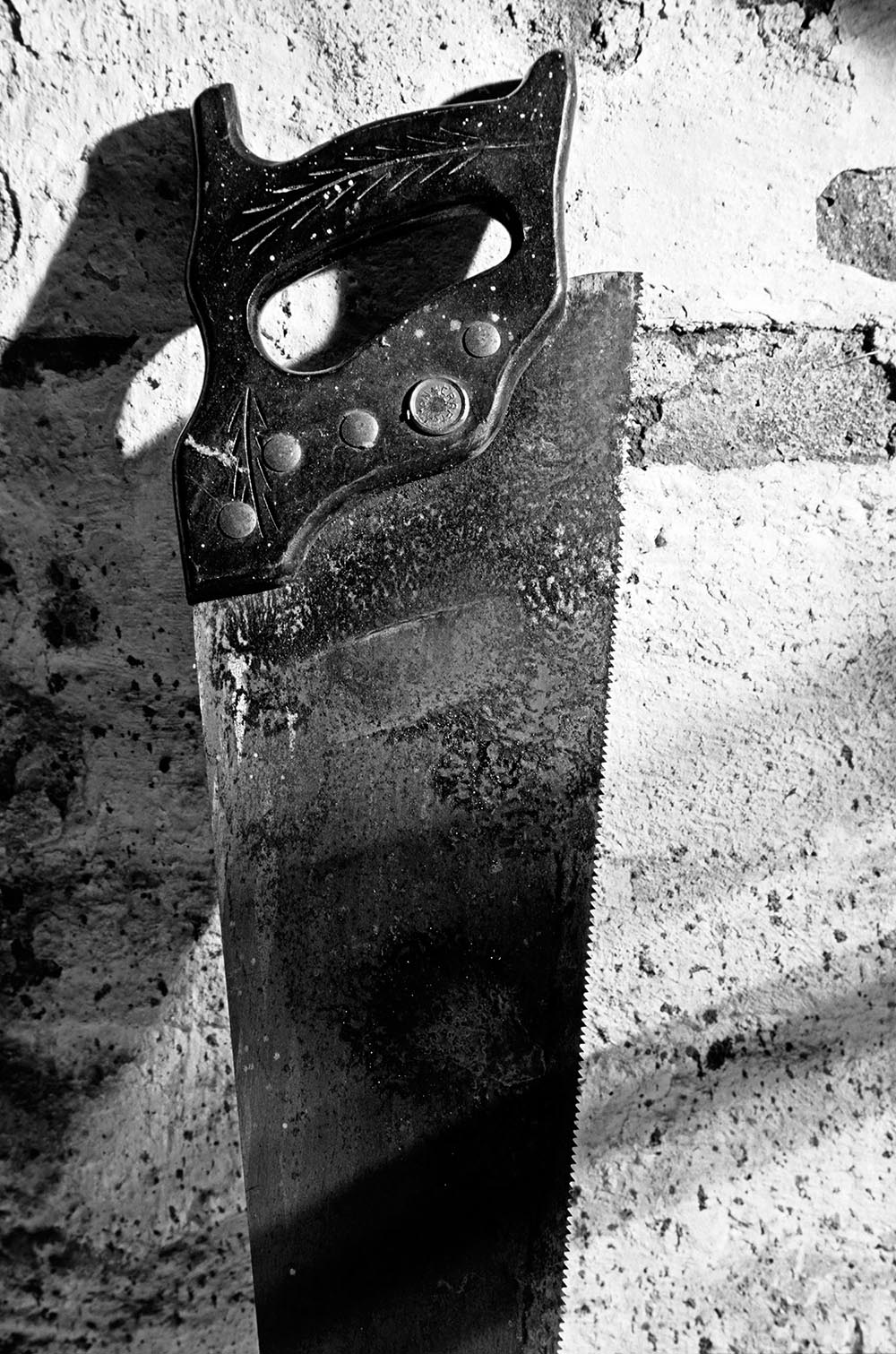 Black and white photograph of an old rusted saw with worn down teeth.