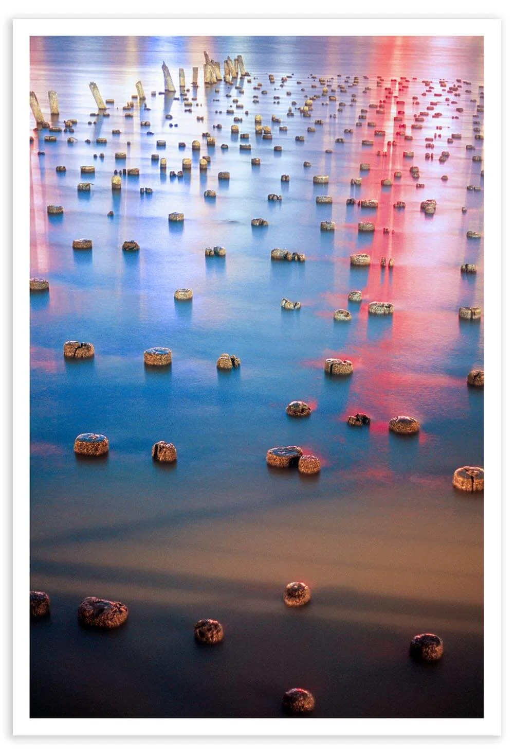 This photo was taken in Weehawken, NJ. The colors in the Hudson River are a reflection of the New York City skyline. The wooden pylons are remnants of an old pier.