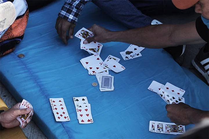 Playing cards outside Benito Juarez stadium complex. Zona Norte, Tijuana. November, 2018. Central American migrants pass the time outside the stadium complex in Tijuana’s “North District” where currently 4,500 migrants are currently housed under tents and tarps. Helicopters fly overhead 24 hours a day. The border lies less than 100 feet.