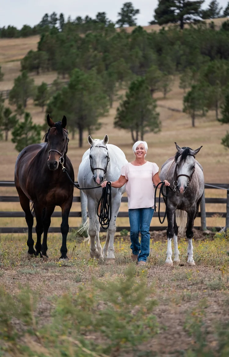 Lee Dudley standing with three horses