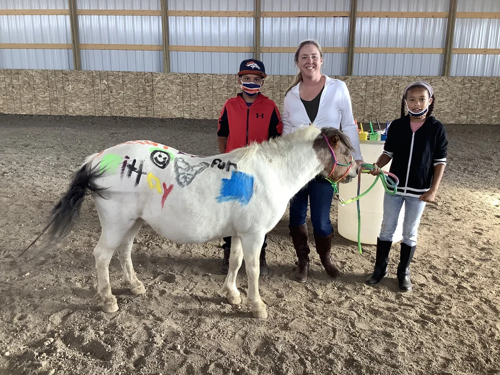 Children and a mentor with a painted horse in the arena