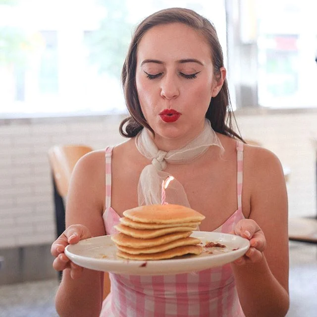 INT. DINER - DAY
Busy waiters pass out eggs and coffee to faces hidden by menus and newspapers. Between two girls, a hand places a tall stack of pancakes topped with a tiny flame.
🎂🥞🎂🥞🎂
🥞Birthday panCAKEs🥞Ya know, in case anyone forgot I eat a