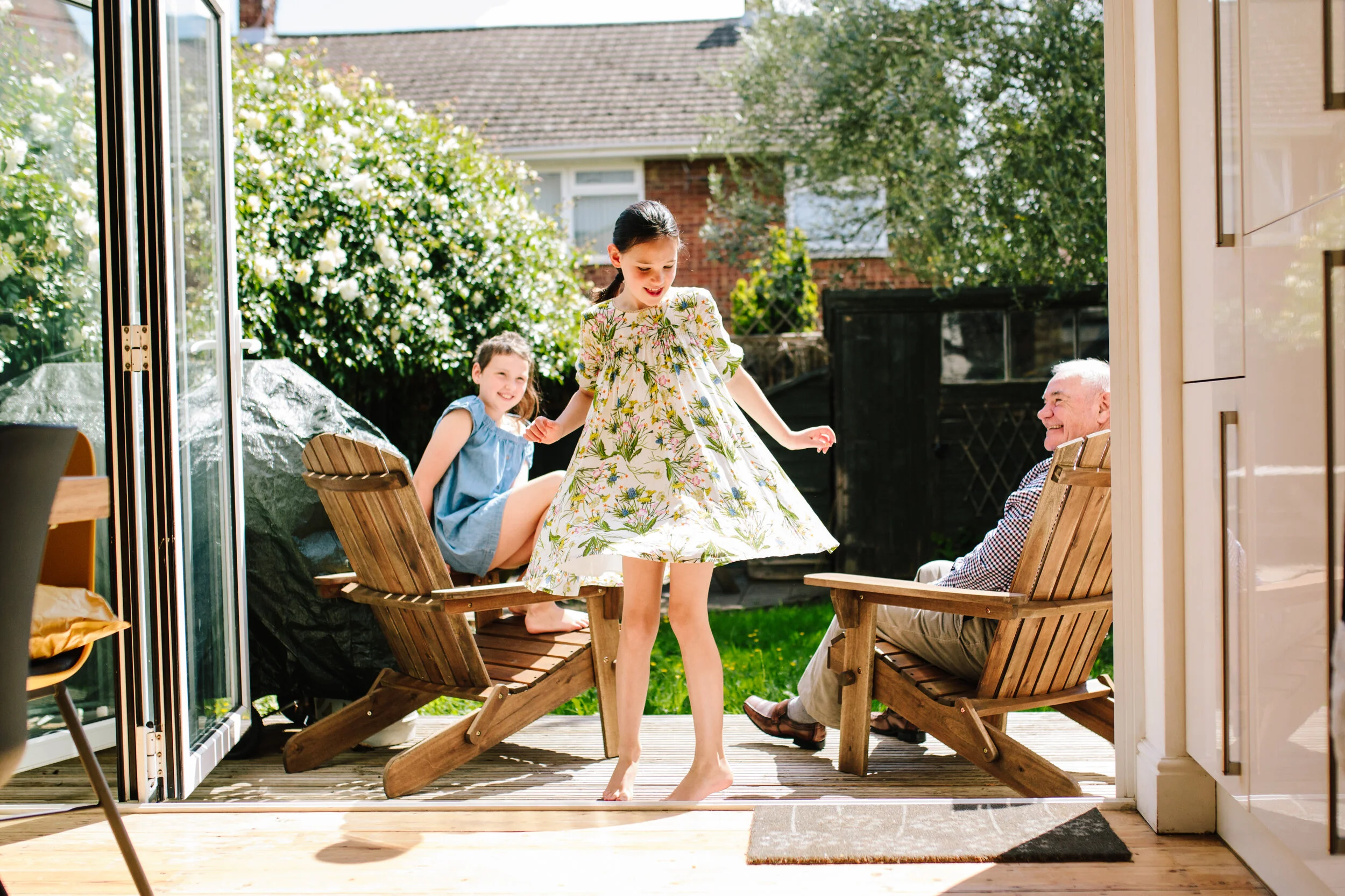 Girl spins for laughing grandad and sister during in home London Family Photoshoot