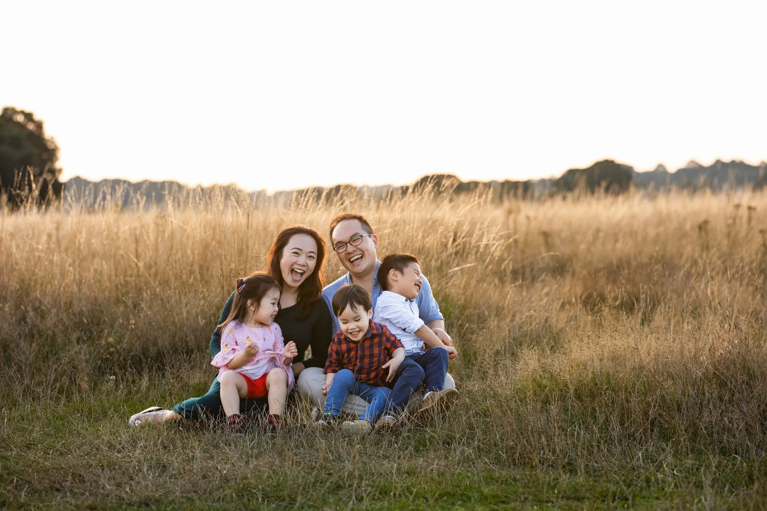 A family giggle infront of their golden hour Richmond Park photoshoot for professional London photographer