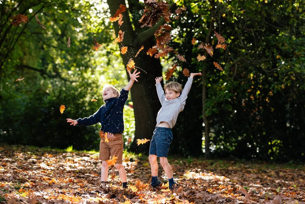 Boys throw leaves in the air in beautiful backlit autumn photoshoot in Wimbledon