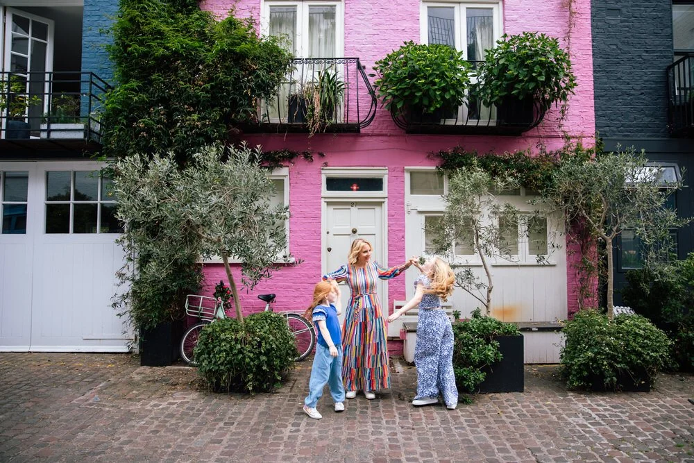 Mum and daughters spin ifront of charming colourful mews house in Notting Hill
