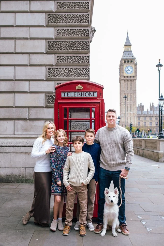 A cute family and their dog pose by a red telephone box infront of Big Ben for London Family Photographer