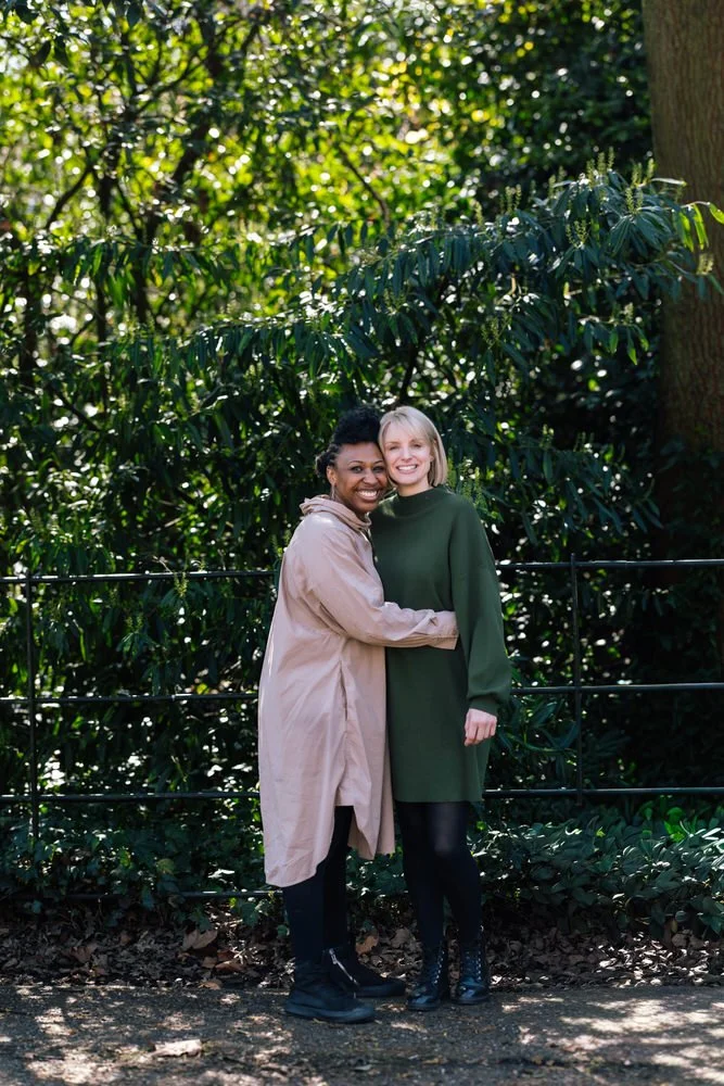 Two mums pose for a couples photo during LGBTQ friendly family photoshoot in Battersea Park