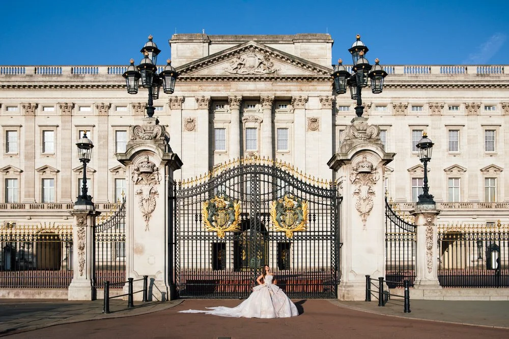 Girl in beautiful Ballgown stands in the sunlight infront of Buckingham Palace