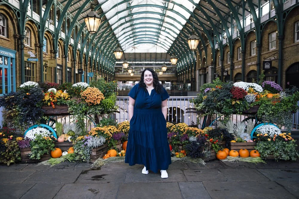 Woman in blue dress poses infront of floral display in Covent Garden for Solo Traveller photoshoot