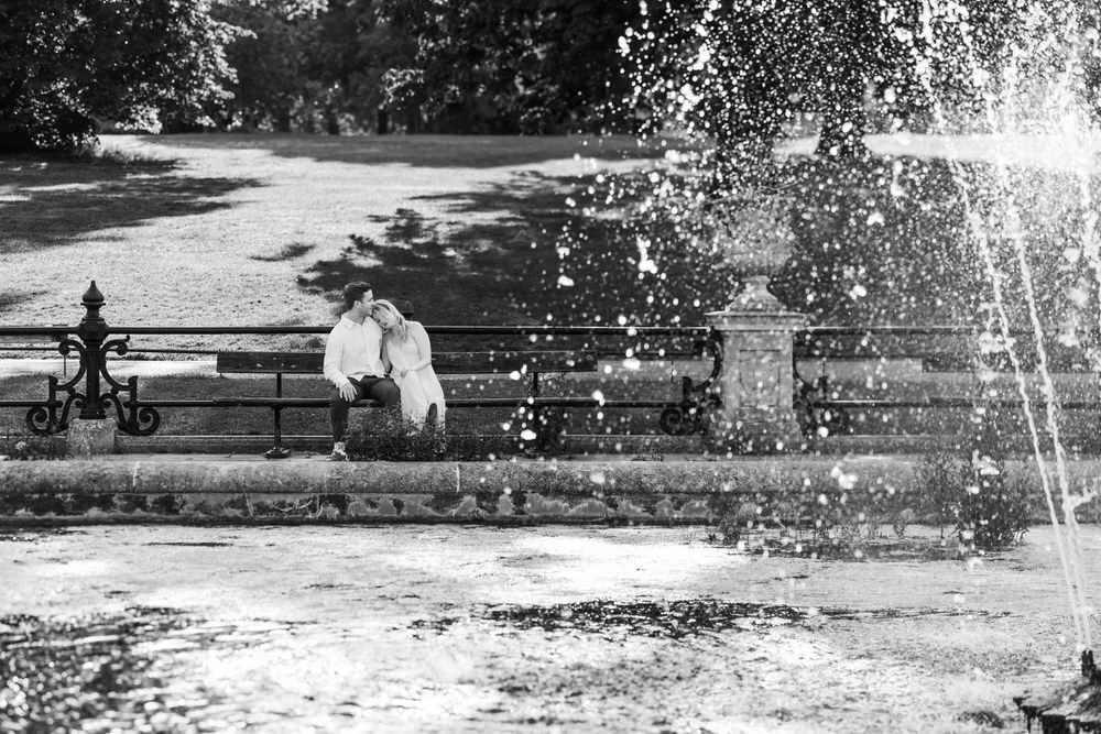 Couple snuggle on bench after romantic proposal in Kensington Gardens London