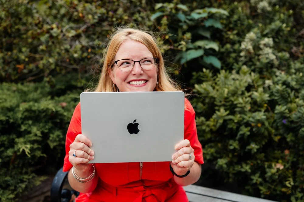 Kirsty holds onto her laptop while smiling off screen