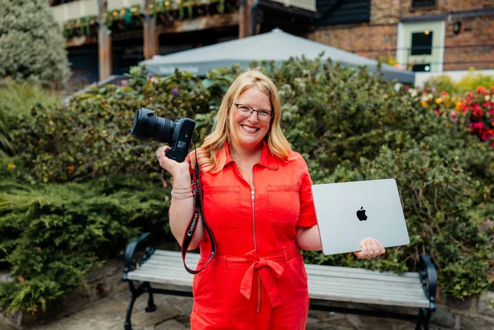 Kirsty Hamilton Photography Business Mentor juggles a camera and her laptop while smiling
