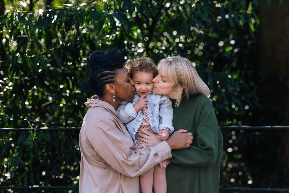 Two mums kiss their daughter during heartwarming family photoshoot in Battersea Park