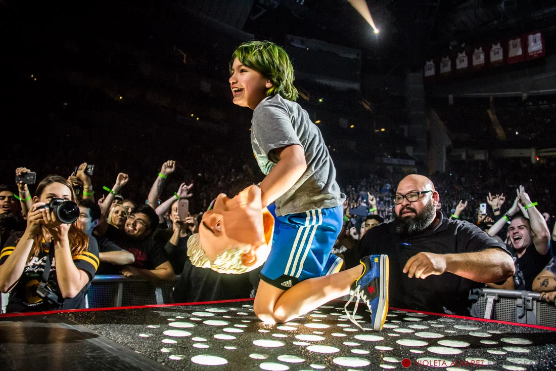 A young fan hops on stage with Green Day
